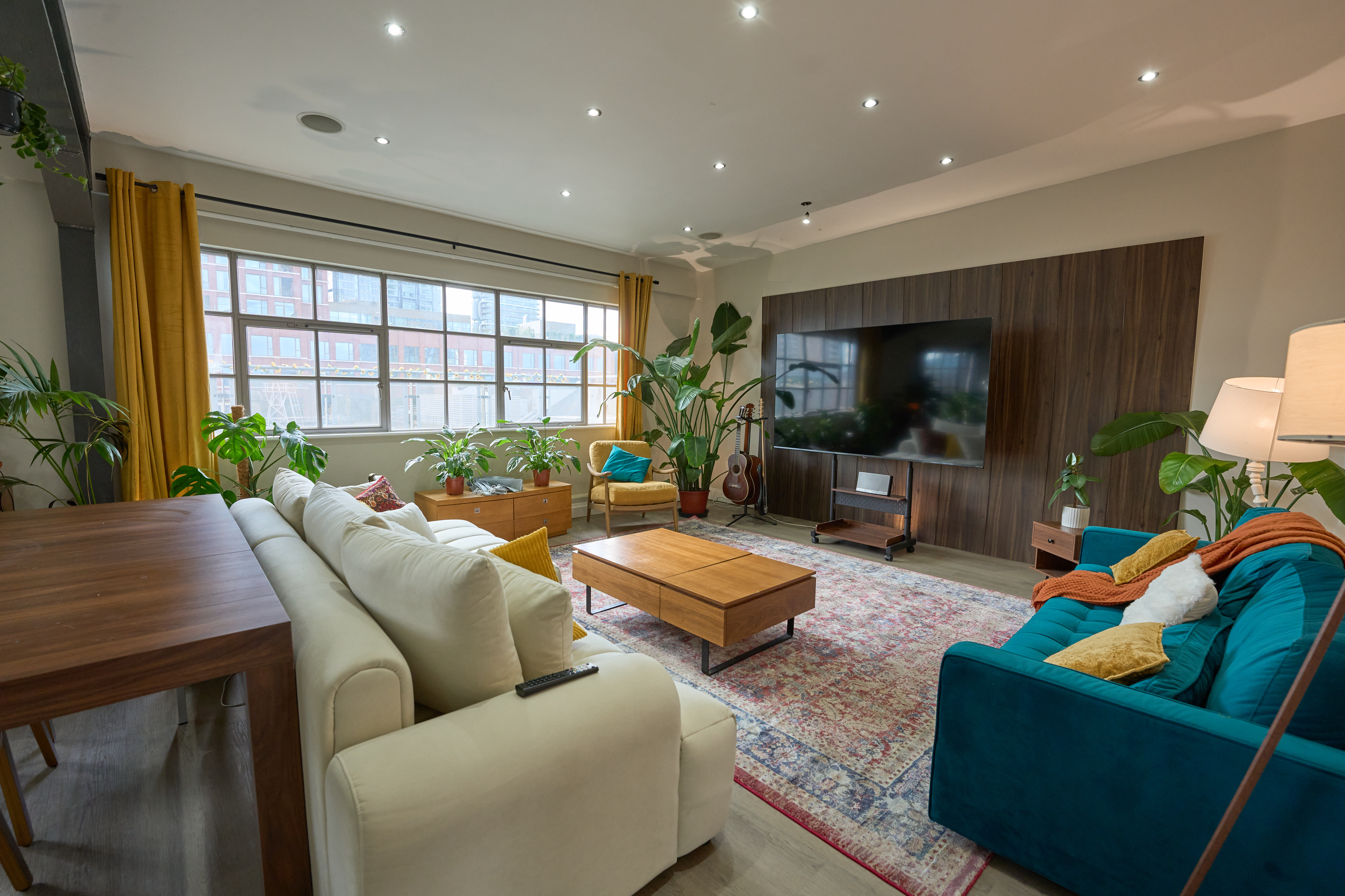 Warm lounge with cream modular sofa, teal velvet sofa, and Persian rug in the Old Street penthouse